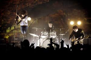 Banda de rock en concierto con el guitarrista saltando frente al público
