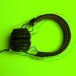 Audífonos sobre fondo verde, para el contenido de como subir canciones a Spotify y otras plataformas digitales