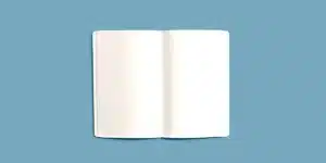 Libreta abierta con páginas en blanco sobre fondo azul grisáceo